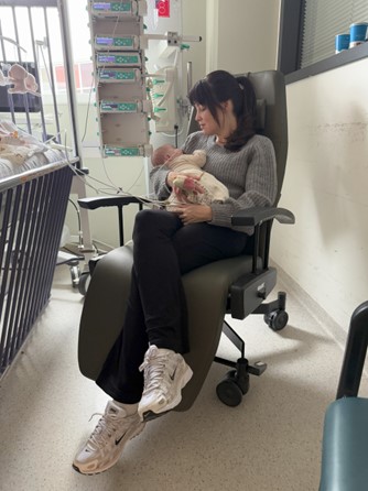 Heidi Klein zit in een stoel van de stichting met haar baby Anne op schoot